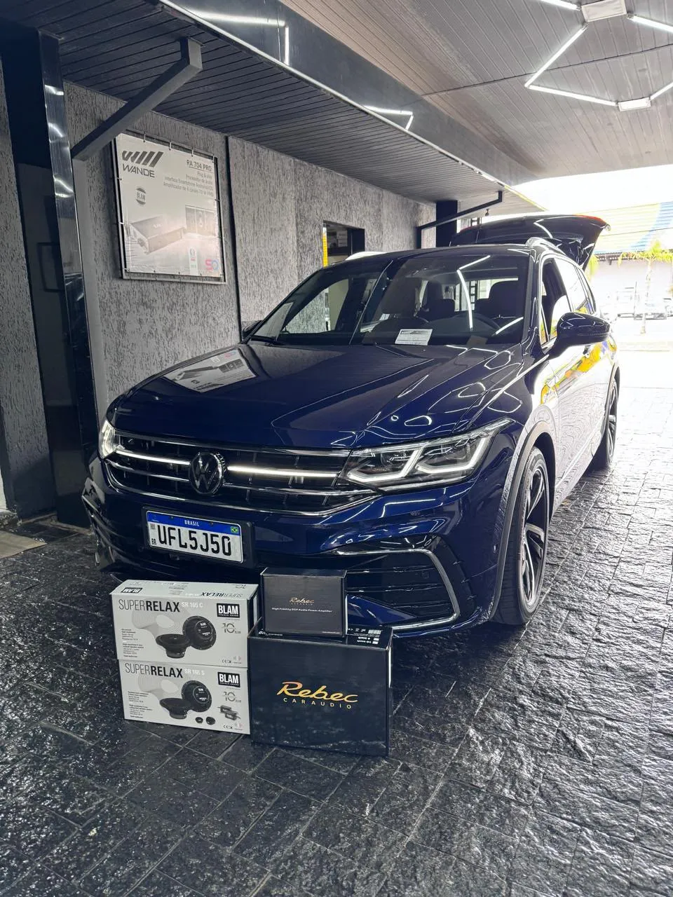 Volkswagen Tiguan azul em frente à loja Wande com os kits de som BLAM e Rebec